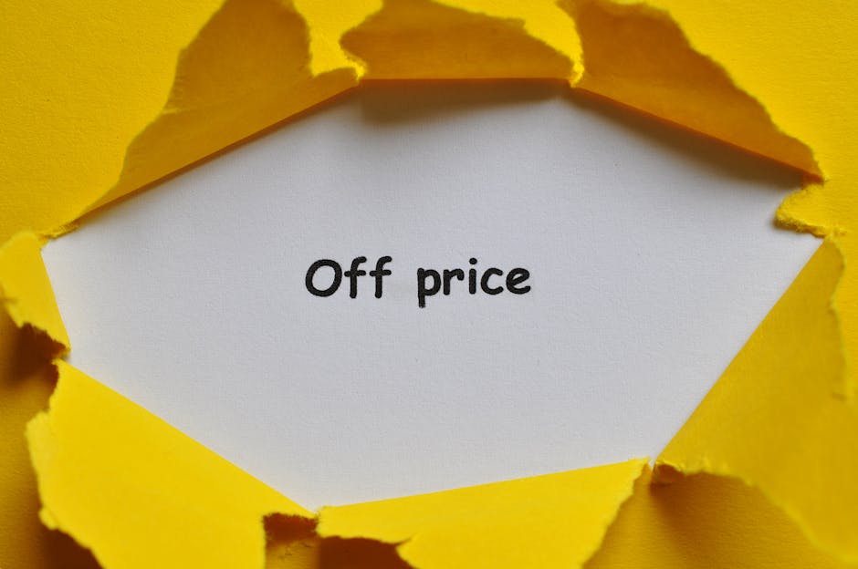 A close-up view of a torn yellow paper wrapping reveals a white card inside with the words 'Off price' printed in black. The torn edges of the yellow paper curl outward, exposing the message clearly. The setting appears to be inside a property or on a flat surface, with lighting that highlights the texture of the paper and card. This visual could relate to packing materials used during home relocation or furniture transport, a service offered by Man with Van Chelsfield who specialise in removals and moving logistics. The image emphasizes the importance of packaging and proper handling during furniture transport and packing and moving processes, illustrating the careful wrapping involved in home relocation tasks.